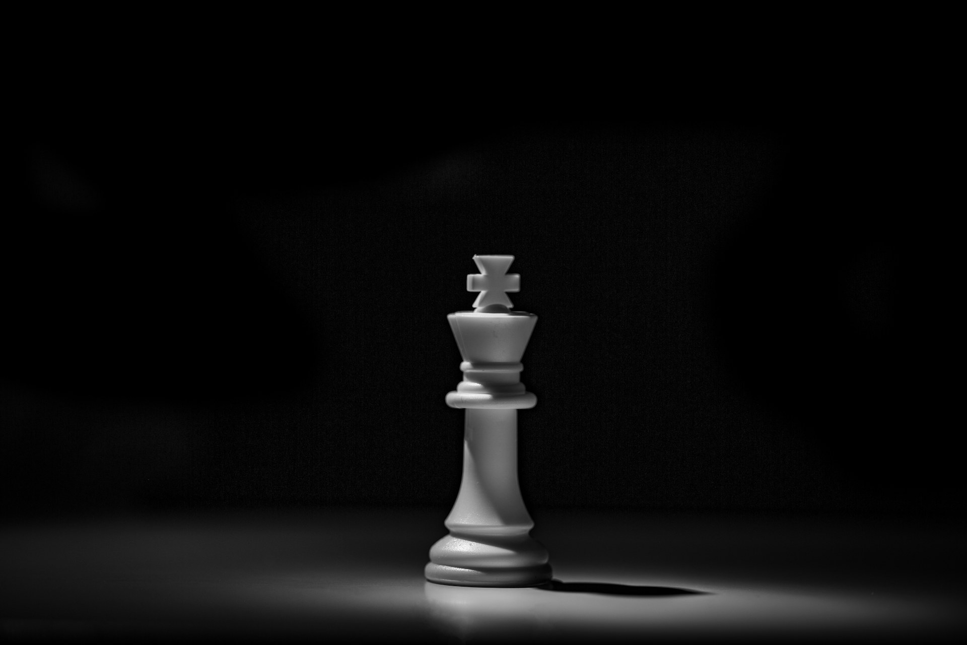 A white chess king in a single pool of light