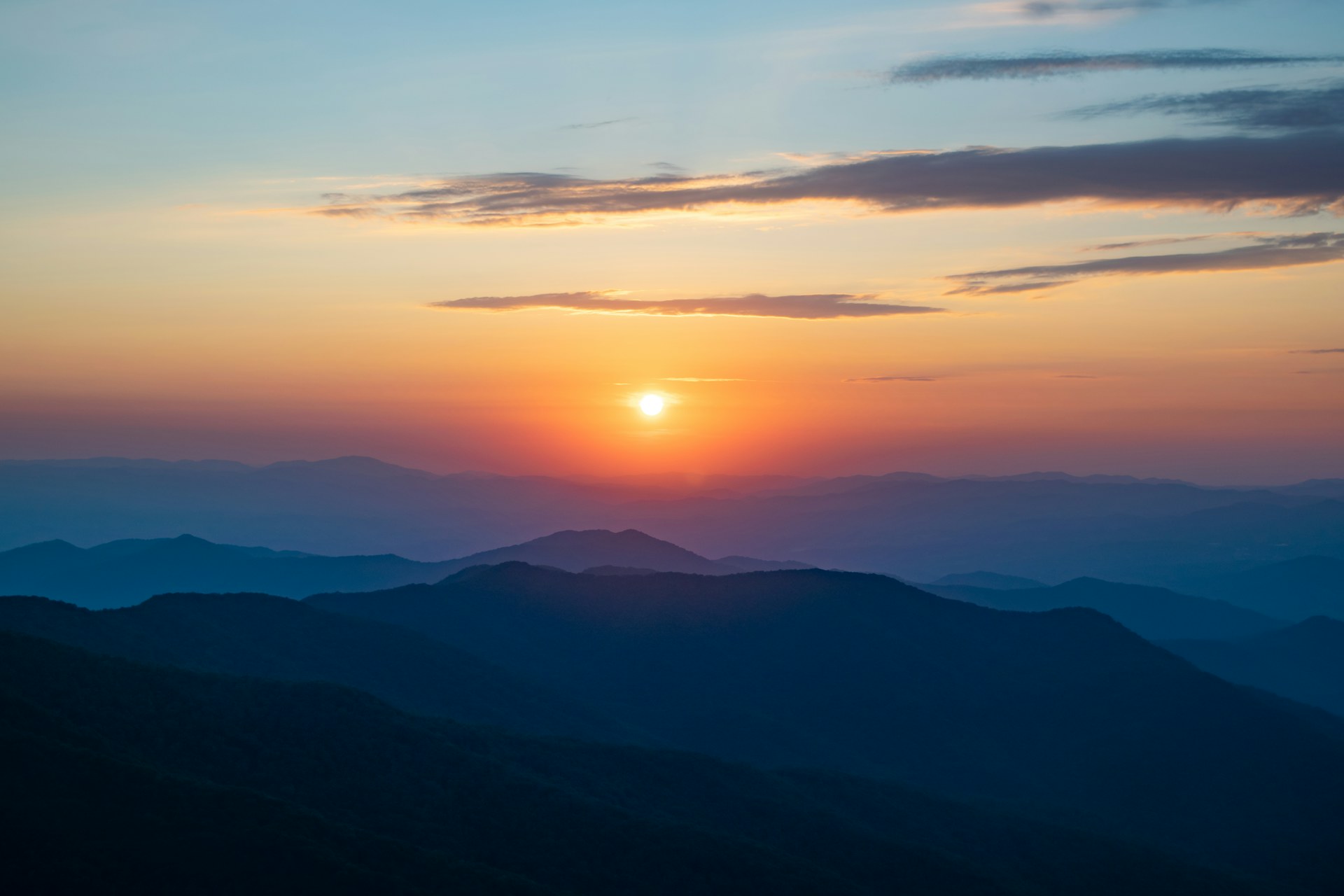 Sunset over layers of distant mountain ridges