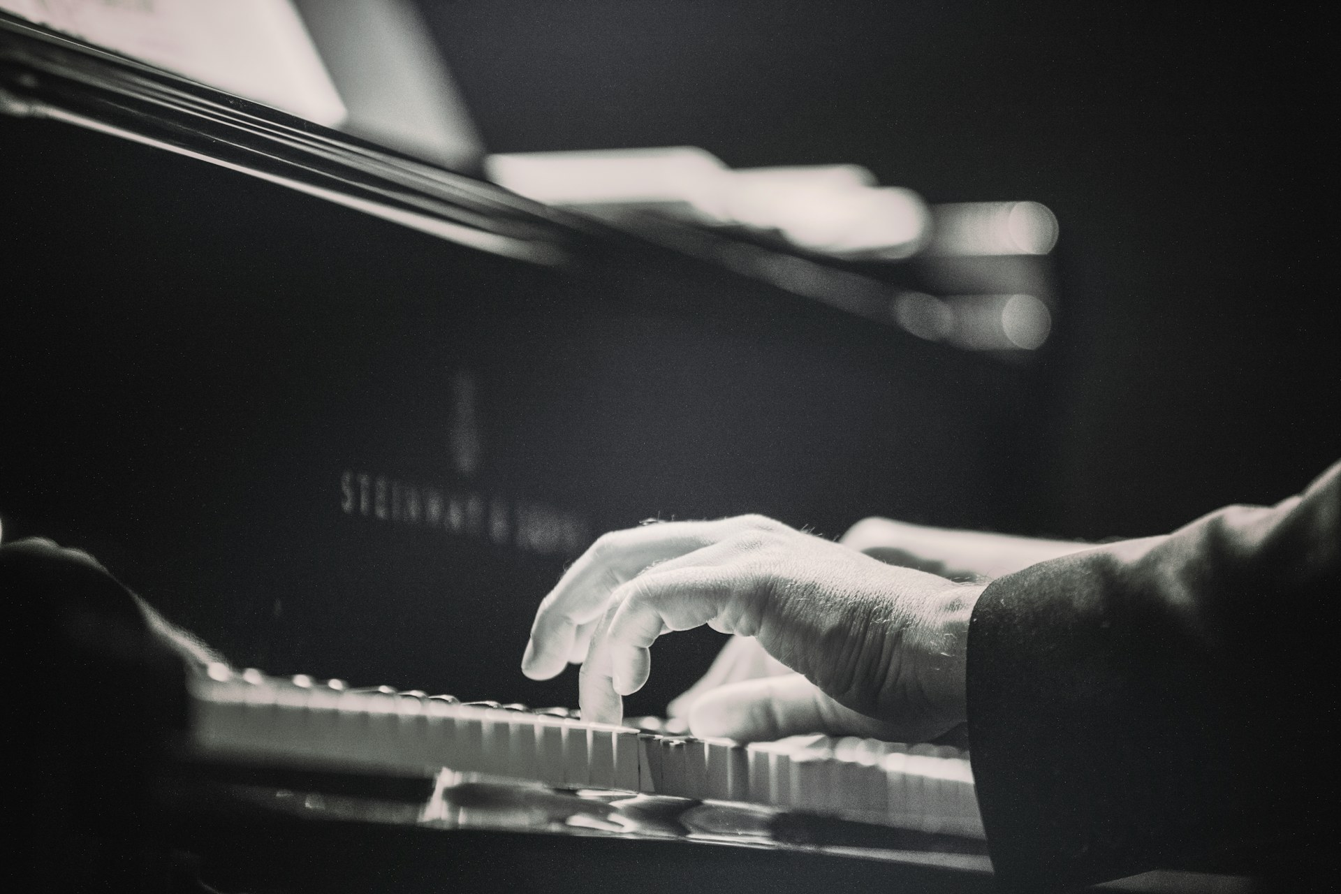 A musician playing a grand piano in soft light